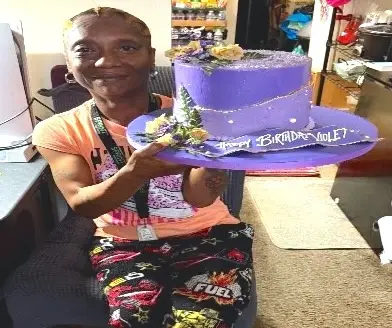 An RCAN volunteer holds a birthday cake prepared for Ms. Davenport, a PDS client.